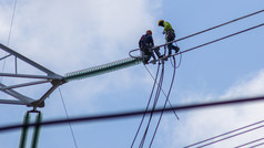电工工作安装高电压电缆高电压安全和系统地在和蓝色的天空背景