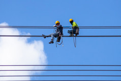 电工工作安装高电压电缆高电压安全和系统地在和蓝色的天空背景