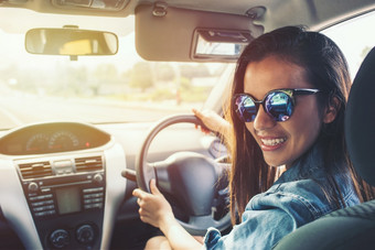 快乐美亚洲女人黑色的头发微笑与太阳镜和蓝色的珍夹克开车车日落图片与过滤器和新浪微博影响