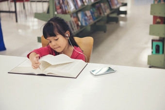 可爱的小孩子们女孩研究读书的<strong>图书馆</strong>房间和<strong>书架</strong>子上背景孩子们听首歌音乐从智能手机表格