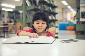 可爱的小孩子们<strong>女孩</strong>研究读书的图书馆房间和书架子上背景孩子们听首歌<strong>音乐</strong>从智能手机表格