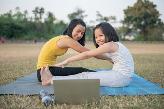 妈妈。和女儿做瑜伽女人和孩子培训的公园户外<strong>体育</strong>健康的<strong>体育</strong>运动生活方式看瑜伽练习在线<strong>视频</strong>教程和坐着向前弯曲构成