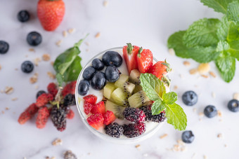 自制的牛奶什锦早餐碗燕麦格兰诺拉麦片与酸奶新鲜的蓝莓桑草莓猕猴桃薄荷和坚果董事会为健康的早餐复制空间健康的早餐概念清洁吃