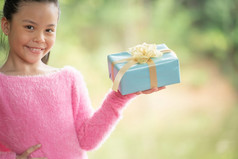 圣诞节肖像快乐微笑小女孩孩子与礼物盒子附近绿色分支树绿色叶子散景出焦点背景从自然森林