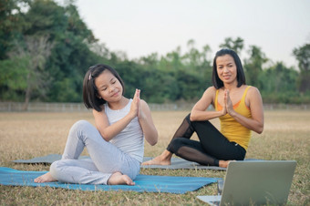 妈妈。和女儿做瑜伽女人和孩子培训公园户外<strong>体育</strong>健康的<strong>体育</strong>运动生活方式看瑜伽练习在线<strong>视频</strong>教程和伸展运动阿尔达matsyendrasana构成