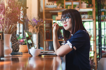 亚洲年轻的业务女人工作使请注意某物使笔记咖啡商店就像的背景