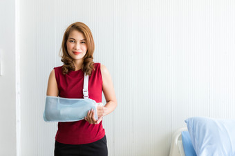 肖像亚洲女病人红色的衣服破碎的手臂后事故和穿手臂<strong>夹板</strong>为治疗和床上的房间医院背景复制空间