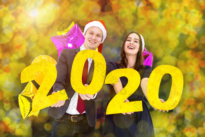 快乐新一年概念夫妇业务西装男人。持有手一年标签和色彩鲜艳的气球与幸福脸庆祝新聚会，派对黄色的色彩斑斓的圆形散景背景