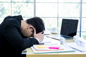 强调商人工作与移动PC电脑和有头疼后业务损失的办公室房间背景