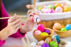 复活节假期概念关闭快乐亚洲年轻的女人手画鸡蛋为复活节与色彩斑斓的复活节鸡蛋的白色房间背景