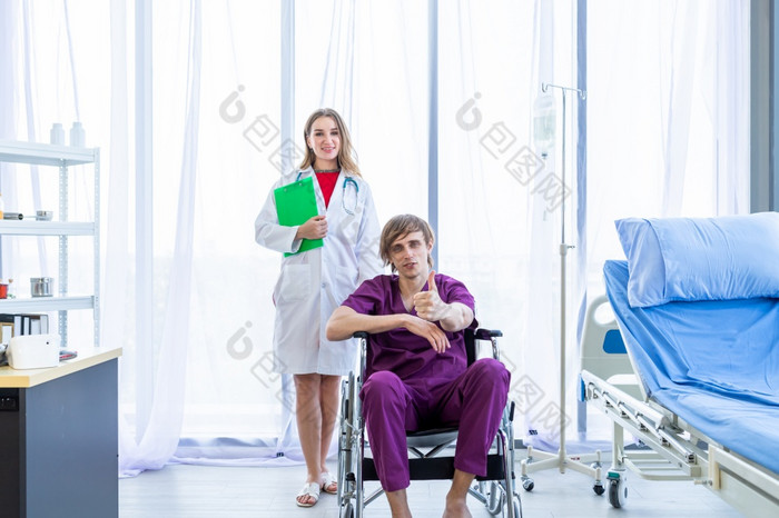男人。病人坐轮椅显示显示拇指与笑脸脸非常好症状和女医生治疗建议与积极的情绪医院背景