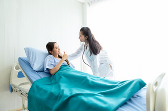 亚洲年轻的女病人床上显示拇指与笑脸脸非常好症状亚洲年轻的女医生<strong>医院背景</strong>