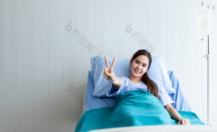 亚洲年轻的女病人笑脸脸电梯两个手指战斗与疾病床上的房间医院背景