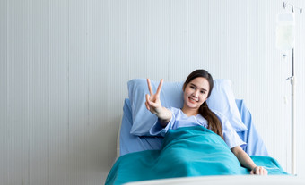 亚洲年轻的女病人笑脸脸电梯两个手指战斗与疾<strong>病床</strong>上的房间<strong>医院</strong>背景