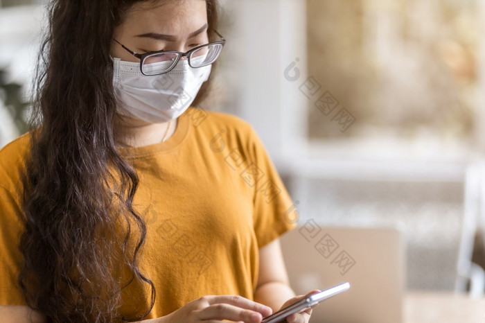 自由人业务女穿保护面具休闲和写作消息智能手机工作与移动PC电脑工作从首页概念预防的传播新冠病毒病毒