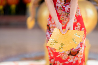 特写镜头女人穿红色的传统的中国人旗袍装饰持有黄色的信封手为中国人新一年节日中国人神社泰国