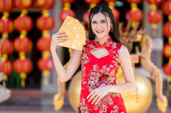 肖像<strong>美丽</strong>的微笑亚洲年轻的女人穿红色的传统的<strong>中国</strong>人旗袍装饰持有黄色的信封手为<strong>中国</strong>人新一年节日<strong>中国</strong>人神社泰国