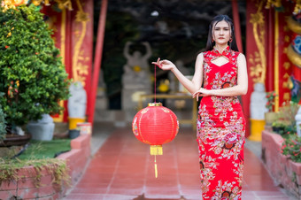 亚洲女人穿红色的传统的中国人旗袍装饰持有纸灯笼与的中国人字母祝福写《财富》杂志祝福赞美装饰为中国人新一年