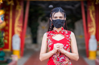 亚洲年轻的女人穿红色的传统的中国人旗袍装饰和穿保护面具细菌为中国人新一<strong>年节</strong>日神社预防的传播新冠病毒病毒