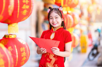 亚洲女孩穿红色的传统的中国人旗袍装饰持有红色的信封手和灯笼与的中国人文本祝福写《财富》杂志祝福为中国人新一年