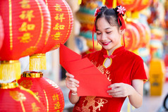 亚洲女孩穿红色的传统的中国人旗袍装饰持有红色的信封手和灯笼与的中国人文本祝福写《财富》杂志祝福为中国人新一年