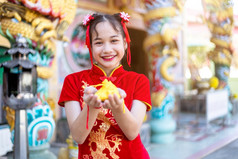 肖像美丽的微笑可爱的小亚洲女孩穿红色的传统的中国人旗袍装饰持有金钱袋为中国人新一年节日中国人神社泰国