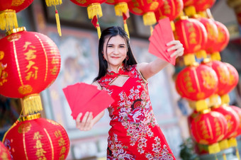 亚洲女人穿<strong>红色</strong>的传统的中国人<strong>旗袍</strong>装饰持有<strong>红色</strong>的信封手和灯笼与的中国人文本祝福写《财富》杂志祝福为中国人新一年