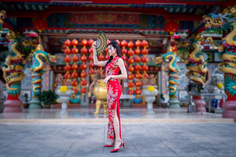 肖像美丽的微笑亚洲年轻的女人穿红色的传统的中国人<strong>旗</strong>袍装饰和持有中国人范宁为中国人新一年节日中国人神社泰国