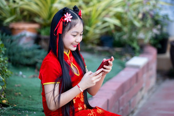 肖像美丽的微笑可爱的小亚洲女孩穿红色的传统的中国人旗袍装饰采取自拍与智能手机为中国人新一年节日中国人神社