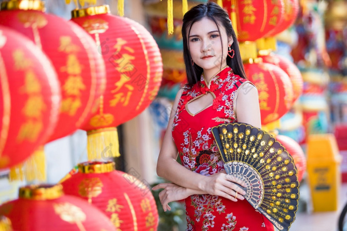 亚洲女人穿红色的传统的中国人旗袍装饰与纸灯笼与的中国人字母祝福写《财富》杂志祝福赞美装饰为中国人新一年