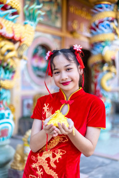 肖像美丽的微笑可爱的小亚洲女孩穿红色的传统的中国人旗袍装饰焦点显示金钱袋为中国人新一年节日中国人神社泰国