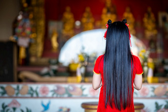 美丽的可爱的小亚洲年轻的女人穿红色的传统的<strong>中国</strong>人<strong>旗袍</strong>装饰站为祈祷佛雕像为<strong>中国</strong>人新一年节日<strong>中国</strong>人神社泰国