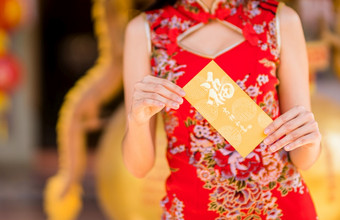 关闭亚洲年轻的女人穿红色的传统的<strong>中国</strong>人<strong>旗袍</strong>装饰持有黄色的信封与的<strong>中国</strong>人文本祝福写好运气为<strong>中国</strong>人新一年节日