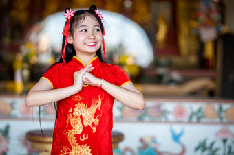 美丽的可爱的小亚洲年轻的<strong>女人</strong>穿红色的传统的中国人旗袍装饰站为祈祷佛雕像为中国人新一年节日中国人神社<strong>泰国</strong>