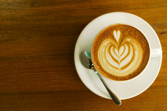 热咖啡拿铁与拿铁艺术牛奶泡沫杯杯子木桌子上前视图早餐咖啡商店的咖啡馆在业务工作概念