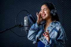 快乐快乐的漂亮的微笑肖像年轻的亚洲女人歌手穿耳机记录首歌前面麦克风专业工作室