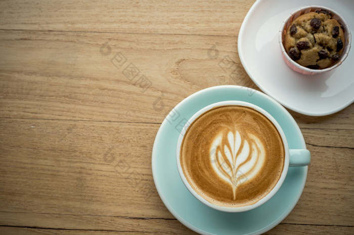 热咖啡拿铁与拿铁艺术牛奶泡沫杯杯子和自制的香蕉杯蛋糕木桌子上前视图早餐咖啡商店的咖啡馆在业务工作概念