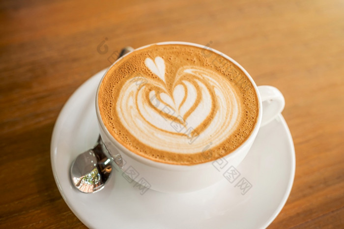 热咖啡拿铁与拿铁艺术牛奶泡沫杯杯子木桌子上前视图早餐咖啡商店的咖啡馆在业务工作概念