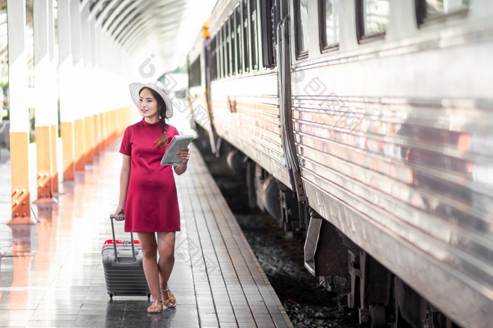 亚洲女人怀孕了红色的衣服旅行与红色的手提箱铁路站旅行旅行者与背包夏天假期概念泰国