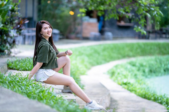 肖像美丽的快乐亚洲女人旅行者穿褐色绿色衣服时尚的赶时髦的人夏天阳光明媚的生活方式的街在户外阳光明媚的夏天一天公园背景