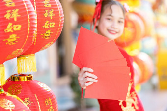 亚洲快乐小女孩穿红色的传统的<strong>中国</strong>人旗袍装饰持有红色的信封手<strong>和</strong>灯笼与的<strong>中国</strong>人文本祝福写《财富》杂志祝福为<strong>中国</strong>人