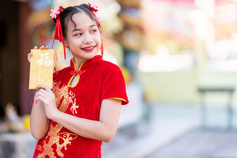肖像可爱的小亚洲女孩穿红色的传统的<strong>中国</strong>人<strong>旗袍</strong>装饰持有黄色的信封与的<strong>中国</strong>人文本祝福写好运气为<strong>中国</strong>人新一年节日