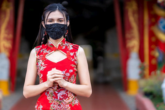 亚洲年轻的女人女人穿红色的旗袍衣服传统的装饰和穿保护面具细菌为中国人新一<strong>年节</strong>日神社预防的传播新冠病毒病毒