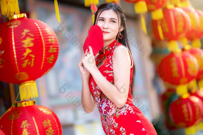 亚洲女人穿红色的旗袍衣服传统的装饰持有红色的信封手和灯笼与的中国人文本祝福写《财富》杂志祝福为中国人新一年