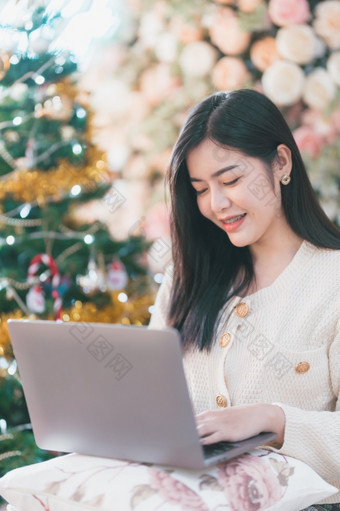 肖像自由业务美丽的积极的微笑年轻的亚洲女人在线工作与移动PC电脑首页的生活房间在室内装饰在圣诞节x-mas和新一年假期