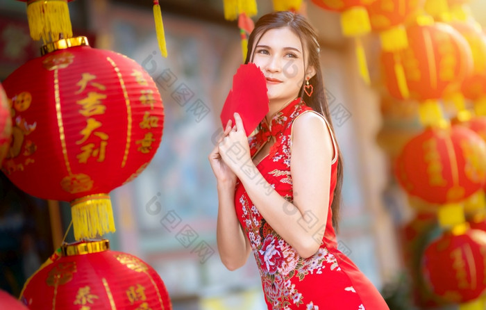 亚洲女人穿红色的旗袍衣服传统的装饰持有红色的信封手和灯笼与的中国人文本祝福写《财富》杂志祝福为中国人新一年