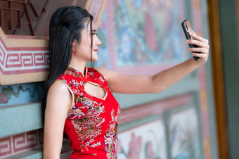 肖像美丽的微笑亚洲年轻的女人穿红色的传统的<strong>中国</strong>人旗袍装饰采取自拍与智能<strong>手机</strong>为<strong>中国</strong>人新一年节<strong>日中国</strong>人神社