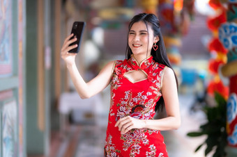 肖像美丽的微笑亚洲年轻的女人穿红色的传统的<strong>中国</strong>人旗袍装饰采取自拍与智能手机为<strong>中国</strong>人新一年节日<strong>中国</strong>人神社