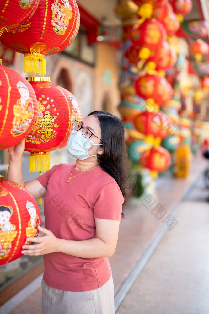 亚洲女人旅行者穿保护面具细菌和红色的与纸灯笼与的中国人文本祝福写《财富》杂志祝福赞美装饰中国人神社中国人新一年