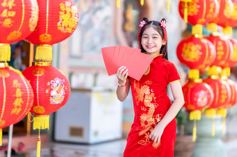 亚洲快乐小女孩穿<strong>红色</strong>的传统的中国人<strong>旗袍</strong>装饰持有<strong>红色</strong>的信封手和灯笼与的中国人文本祝福写《财富》杂志祝福为中国人